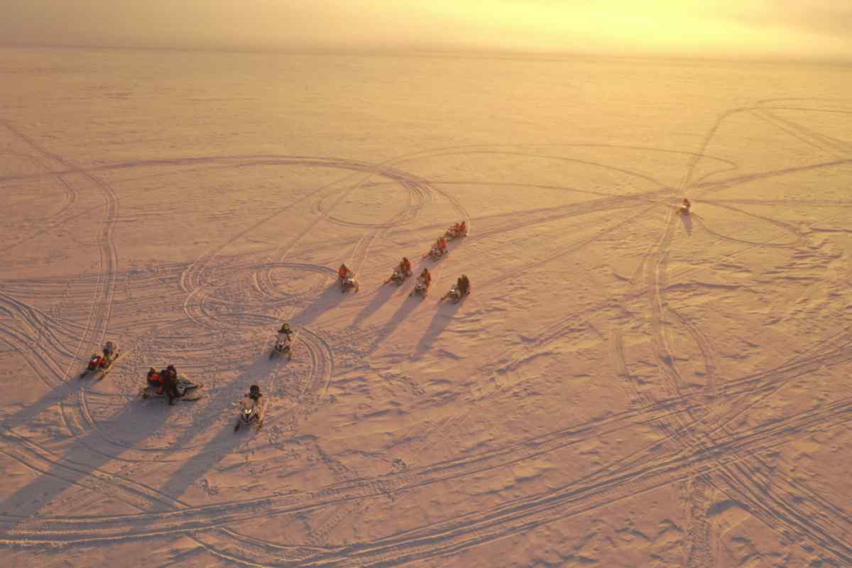 Excursión guiada en moto de nieve sobre la superficie nevada del glaciar Langjökull al atardecer.