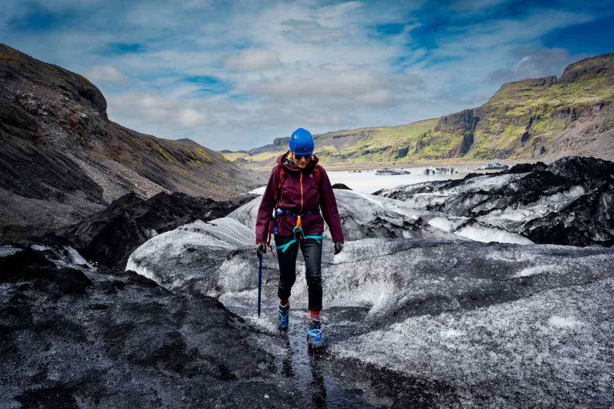 Viajero con equipo para caminar sobre glaciares caminando sobre hielo negro y blanco en Islandia