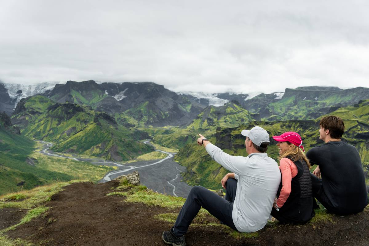 Familia contemplando un frondoso valle islandés y las montañas desde un mirador panorámico